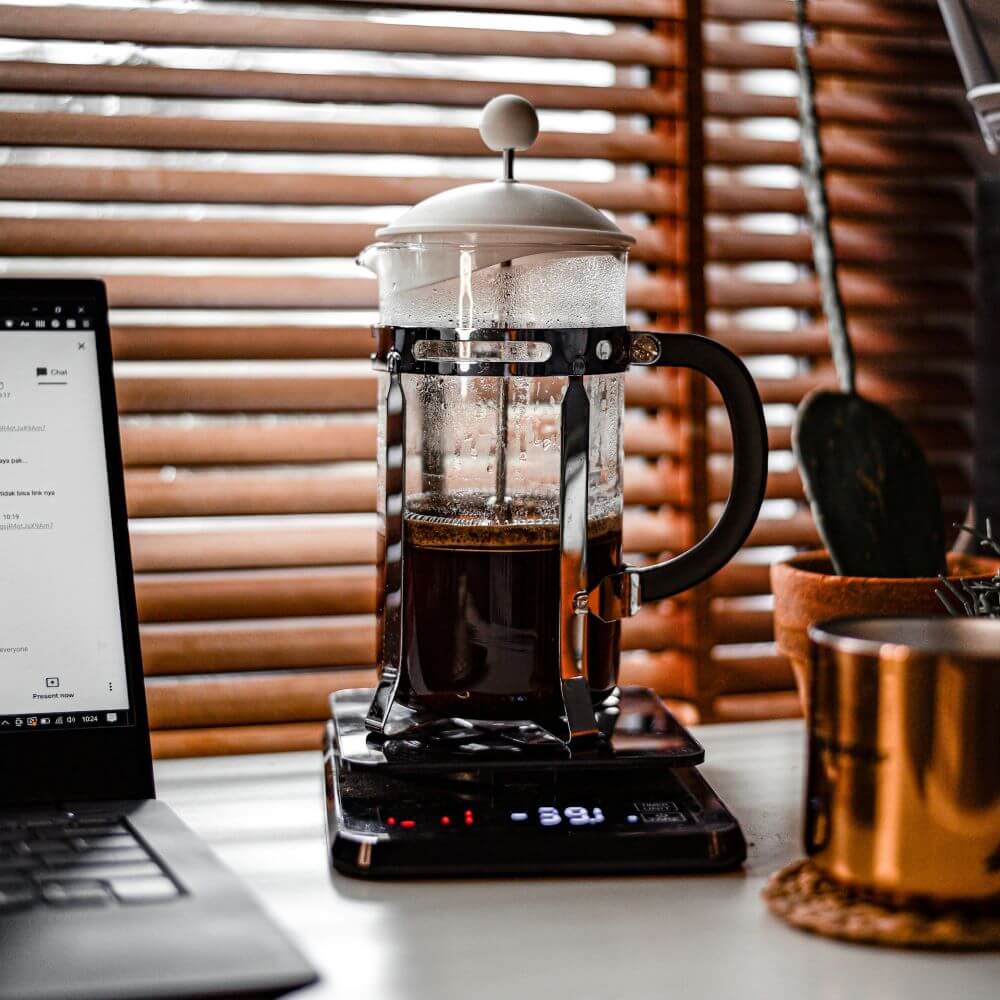 Cafetière à piston posée sur une balance de précision.