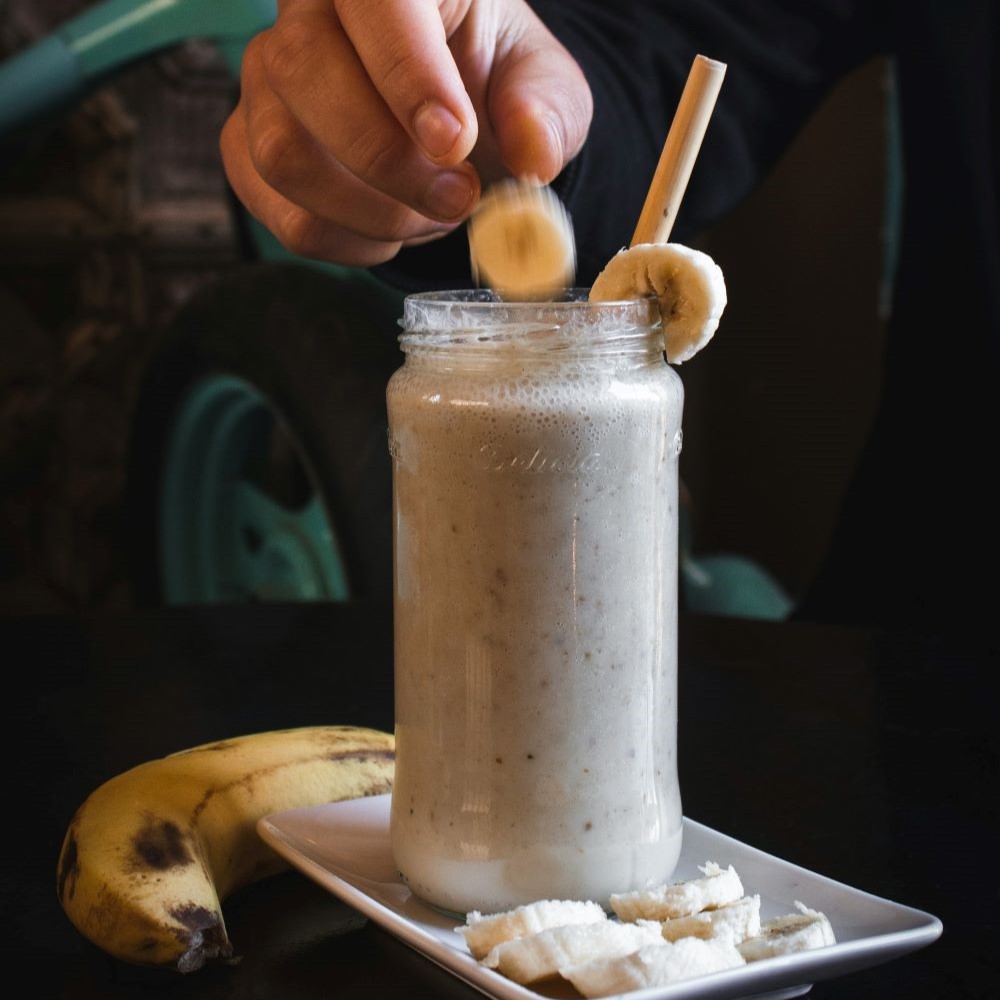 Smoothie au café et à la banane servie avec une paille dans un verre transparent.