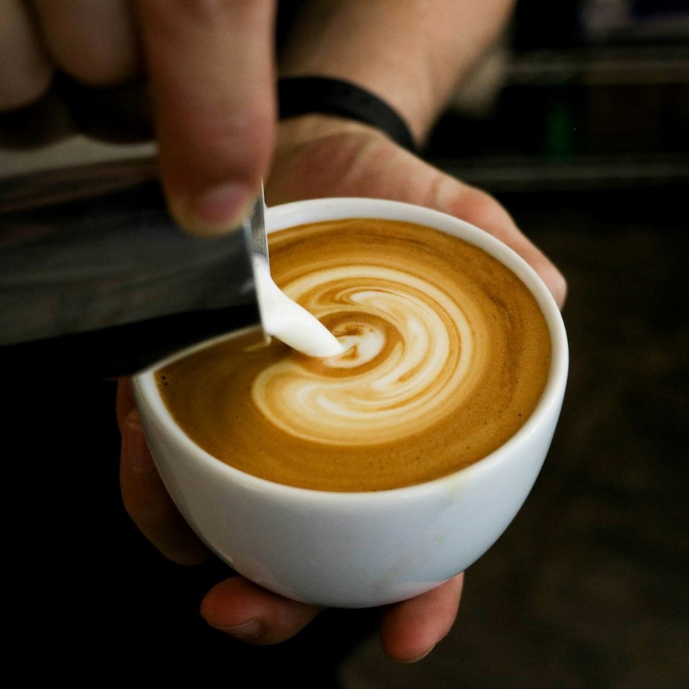 Gros plan sur la préparation d'un latte art.