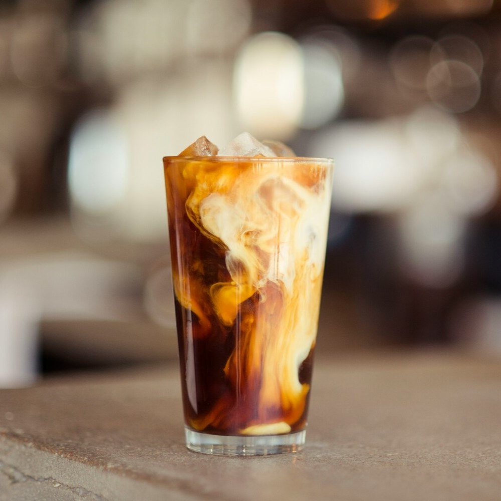 Iced latte dans un grand verre posé sur une table.